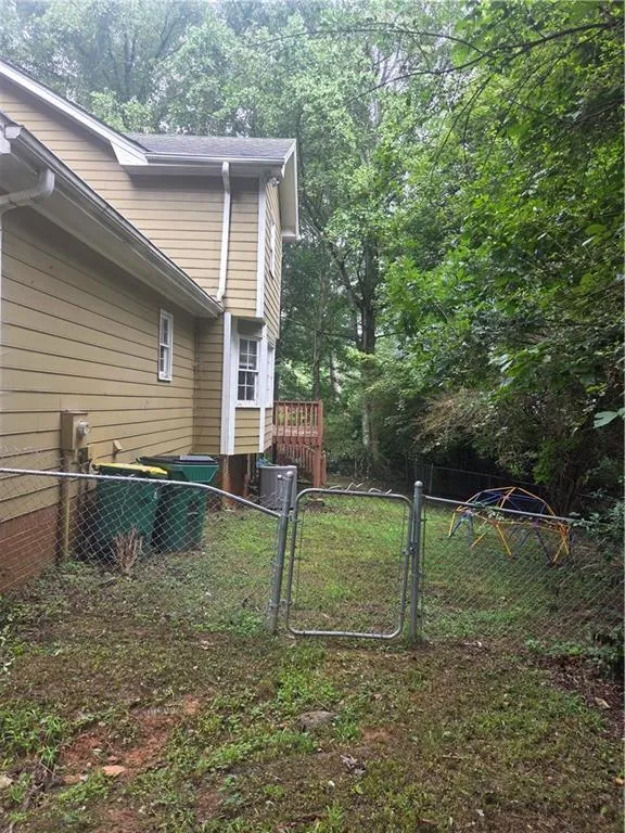 View of side of property featuring a gate and a central AC unit
