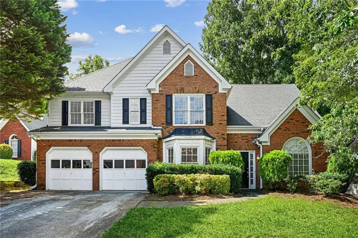 Traditional-style residence featuring a brick and white siding facade with a gabled roof