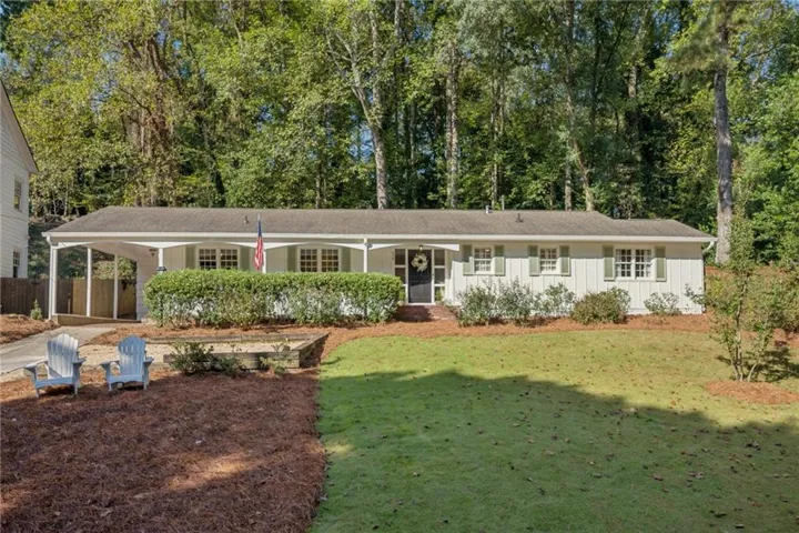 White-sided exterior with green shutters, a front porch, and an attached carport