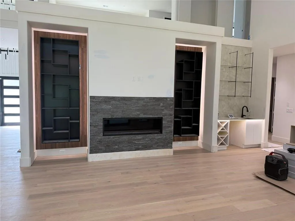 Living area with light wood finished floors, a glass covered fireplace, and a towering ceiling