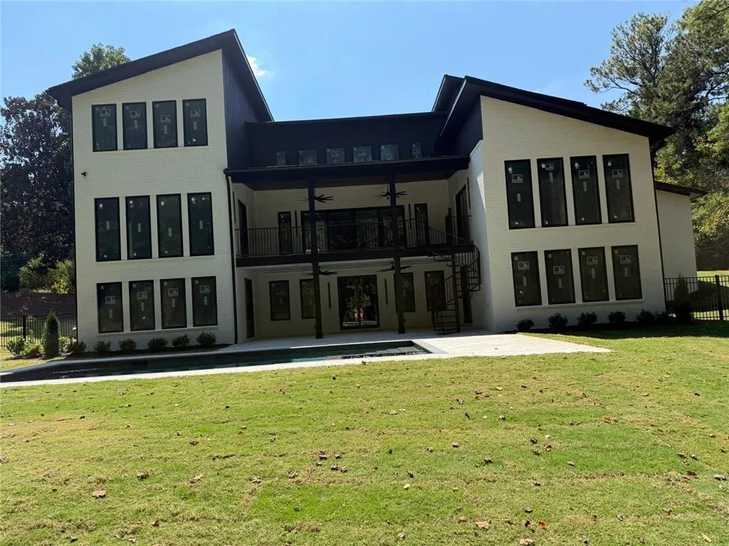 Back of house with a ceiling fan, a balcony, a patio area, and a yard