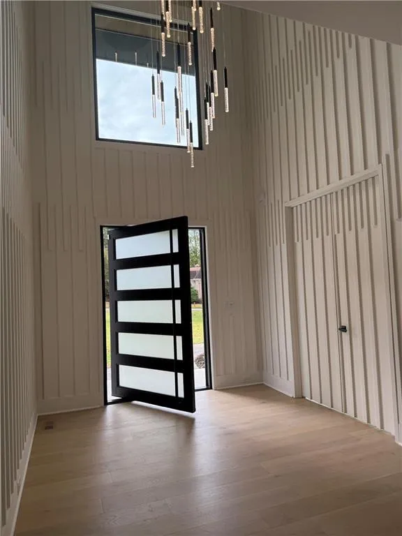 Entrance foyer featuring healthy amount of natural light, a towering ceiling, and light wood-style floors Entrance foyer featuring healthy amount of natural light, a towering ceiling, and light wood-style floors