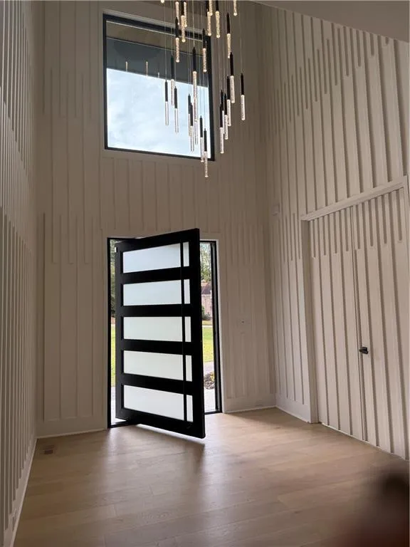 Entrance foyer with light wood-style floors and a towering ceiling