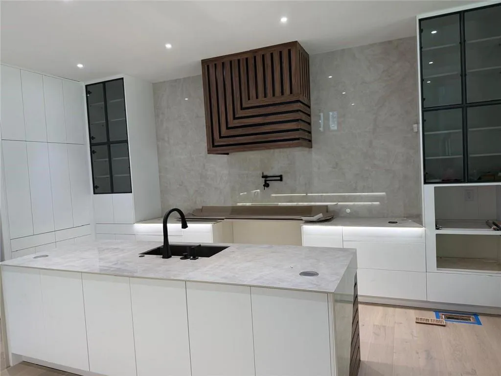 Kitchen featuring glass insert cabinets, light wood-style floors, modern cabinets, light stone counters, and tile walls