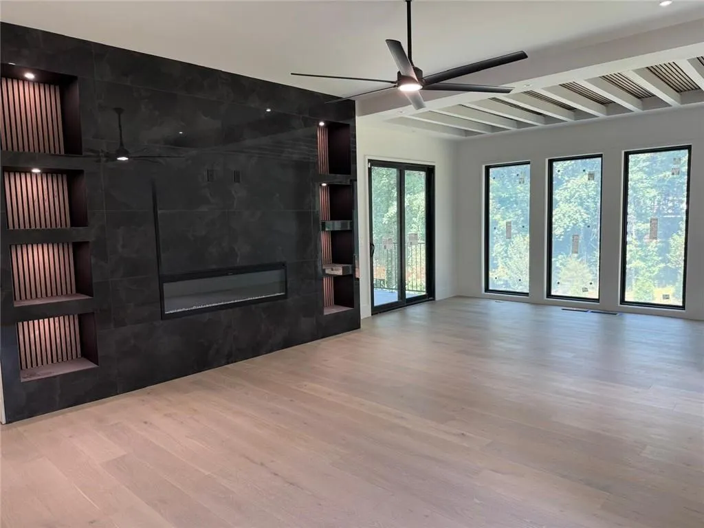 Unfurnished living room with ceiling fan, light wood finished floors, beam ceiling, a tile fireplace, and built in features
