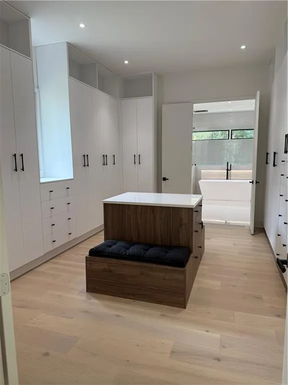 Full bathroom with a soaking tub, light wood-style flooring, and recessed lighting Full bathroom with a soaking tub, light wood-style flooring, and recessed lighting