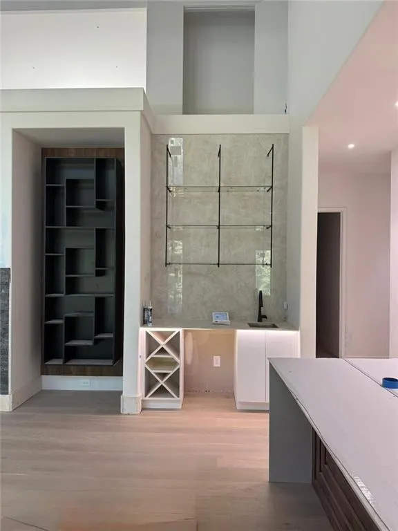 Bar with white cabinetry, light wood finished floors, modern cabinets, and light stone countertops