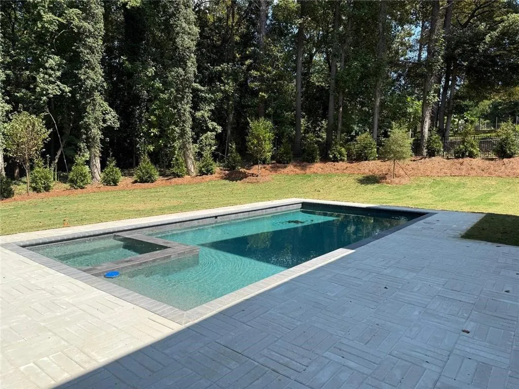 View of pool featuring a pool with connected hot tub, a lawn, and a patio area