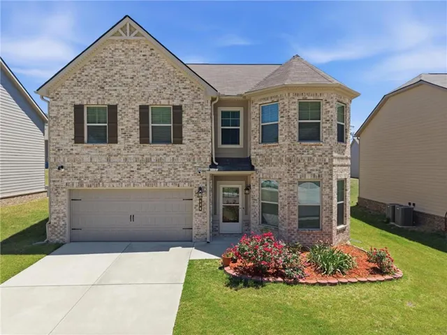Two-story brick facade residence featuring a two-car garage, a turret-style bay window, and a gabled entry