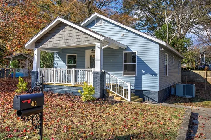 Charming single-story residence featuring light blue siding, a covered front porch with white railing, and dark gray column bases