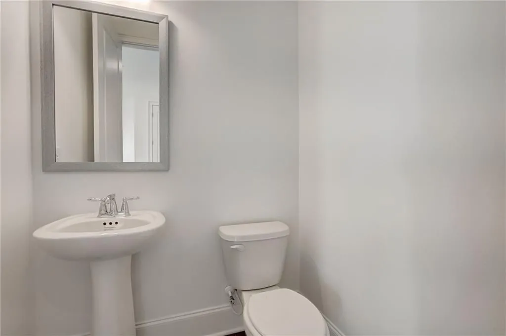 The powder room on the main level features a pedestal sink and hardwood flooring.