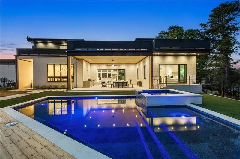 Back of house featuring a ceiling fan, a patio area, a pool with connected hot tub, and a lawn