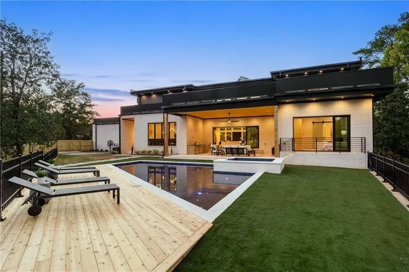 Back of property at dusk with a fenced backyard, a ceiling fan, a patio area, and a pool with connected hot tub
