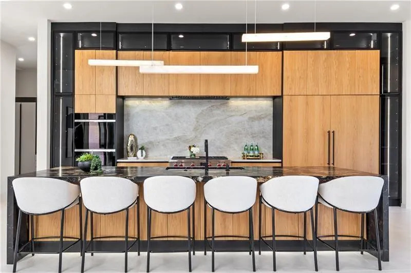 Kitchen with a breakfast bar, modern cabinets, a large island, dark stone countertops, and recessed lighting