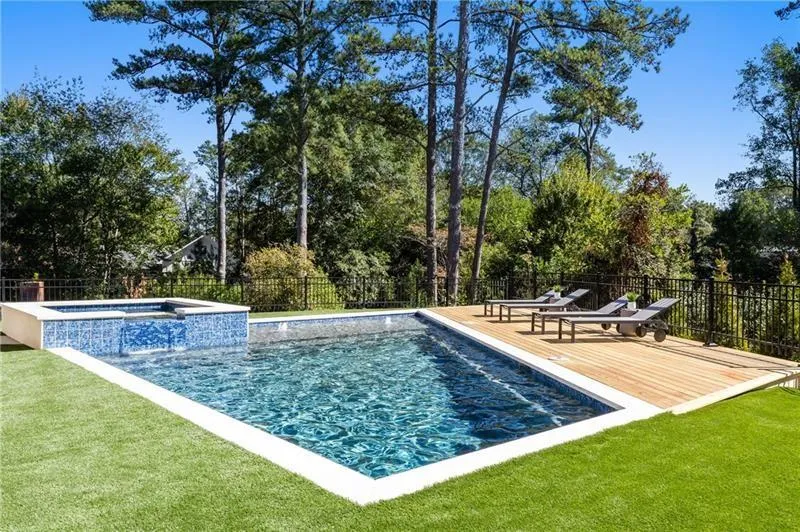View of swimming pool featuring a heated saltwater pool with connected hot tub and a wooden deck.