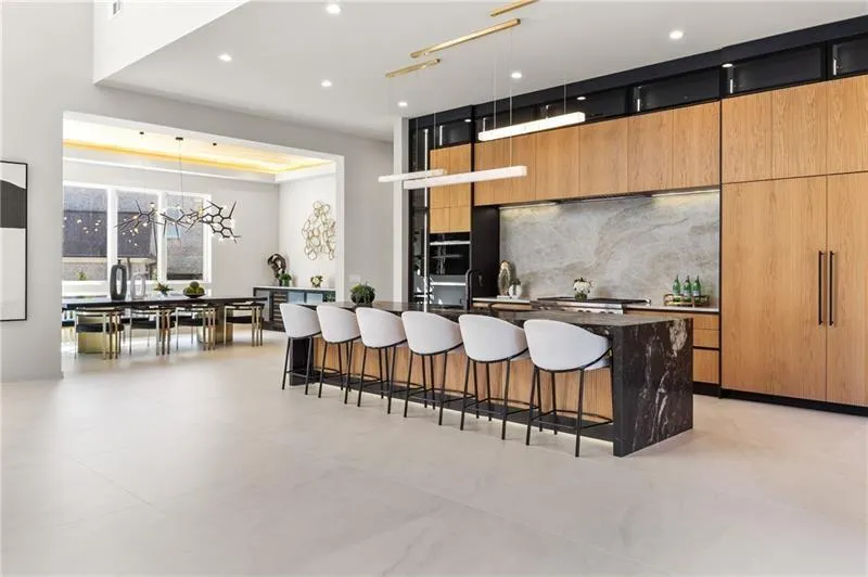 Kitchen with a breakfast bar, decorative light fixtures, a large island with sink, modern cabinets, and dark stone counters