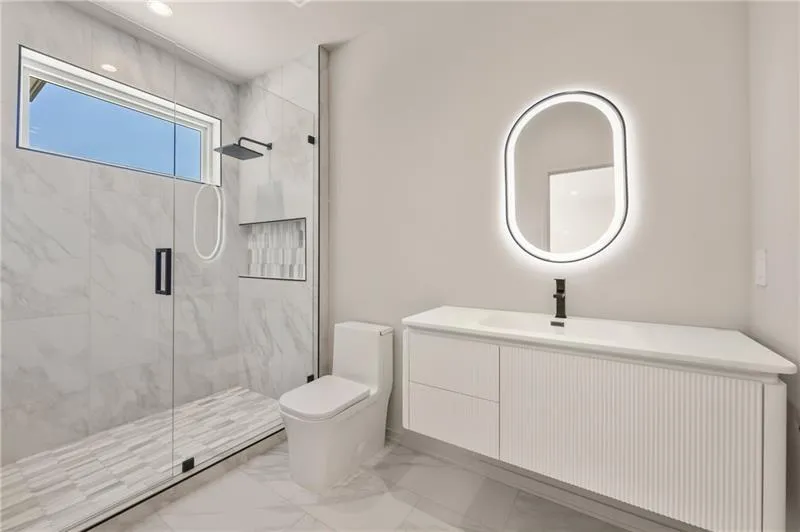 Full bathroom with marble look tiles, vanity, and a marble finish shower