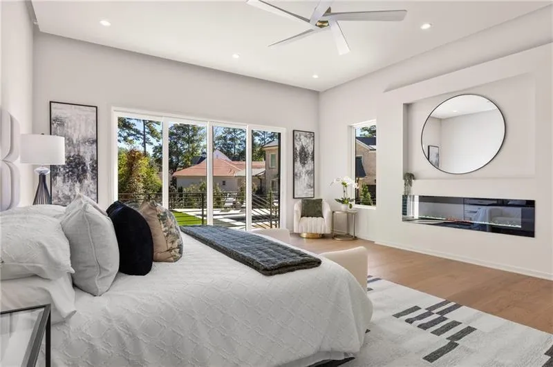 Bedroom with multiple windows, wood finished floors, ceiling fan, a glass covered fireplace, and recessed lighting