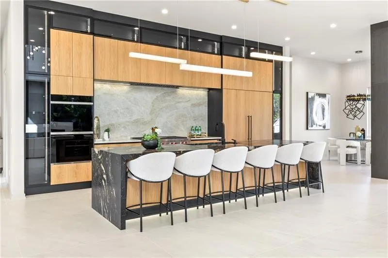 Kitchen with modern cabinets, a kitchen breakfast bar, recessed lighting, a large island with sink, and dark stone counters