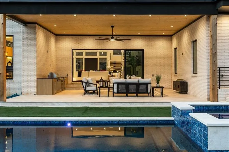 Back of house featuring ceiling fan, an outdoor pool, an outdoor kitchen, a patio, and an in-ground hot tub