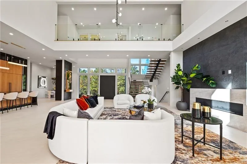 Living room featuring stairs, an accent wall, a high ceiling, and recessed lighting