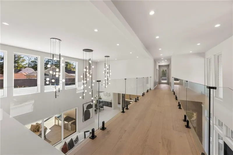 Hall with light wood-style floors and glass railing.