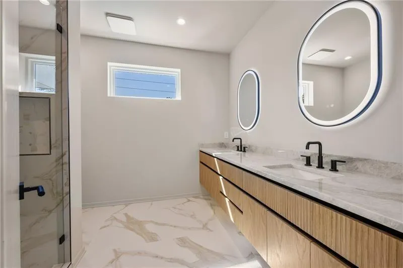 Full bathroom featuring double vanity, light marble finish flooring, a marble finish shower, and recessed lighting