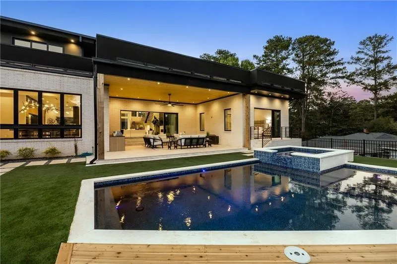 Back of house featuring ceiling fan, a patio, a pool with connected hot tub, and outdoor lounge area