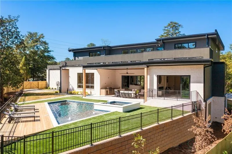 Back of house featuring a fenced backyard, a patio area, brick siding, an in-ground hot tub, and stucco siding