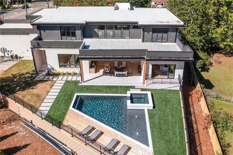 Rear view of house with a patio, stucco siding, a balcony, and a pool with connected hot tub
