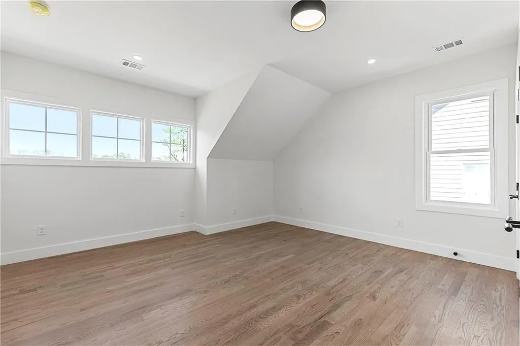 Additional living space with light wood finished floors, lofted ceiling, and recessed lighting