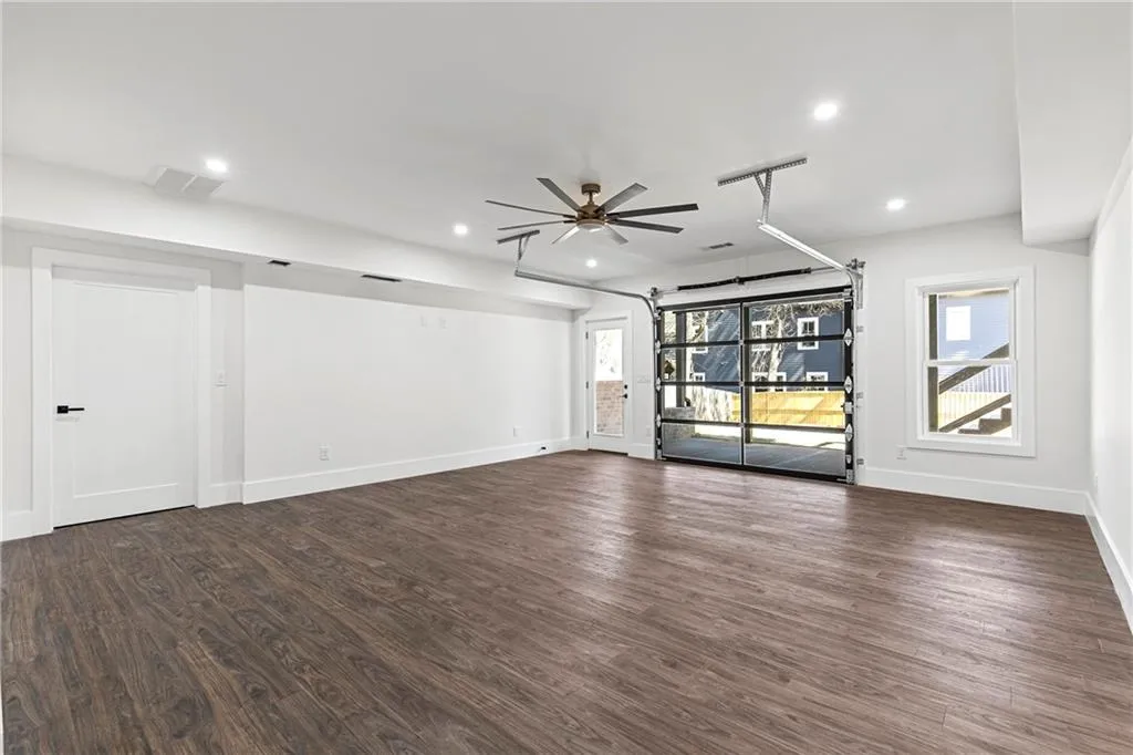 Unfurnished living room with a garage, dark wood-style floors, and recessed lighting
