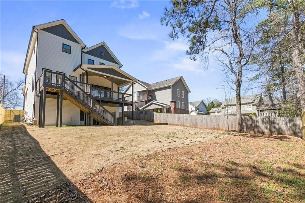 Back of house featuring a fenced backyard, a wooden deck, stairway, board and batten siding, and a residential view
