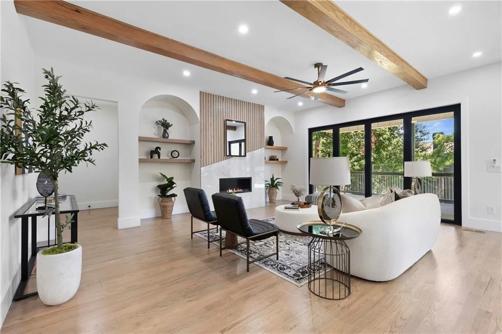 Living area featuring beam ceiling, a ceiling fan, a fireplace, light wood-type flooring, and recessed lighting