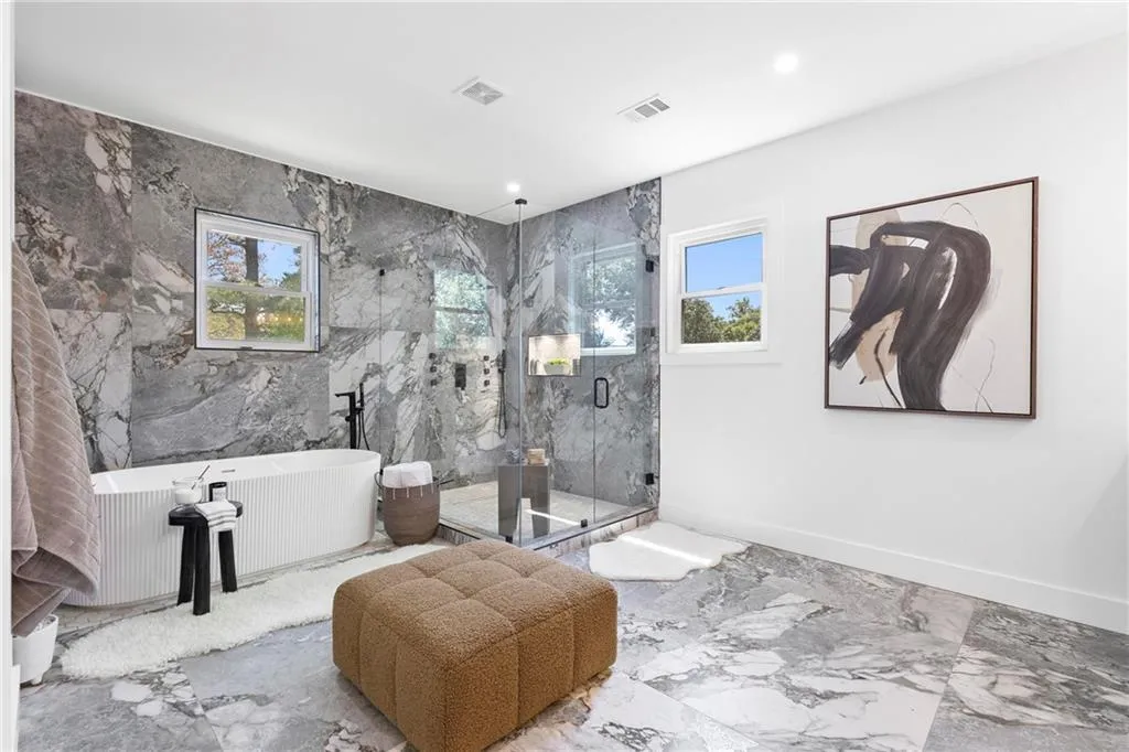 Full bath featuring marble tiled floors, a freestanding tub, a marble finish shower, and recessed lighting
