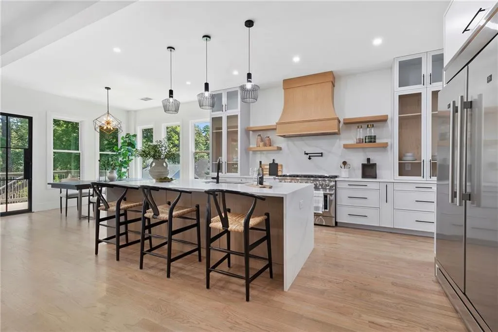 Kitchen with glass insert cabinets, high quality appliances, pendant lighting, decorative backsplash, and a breakfast bar