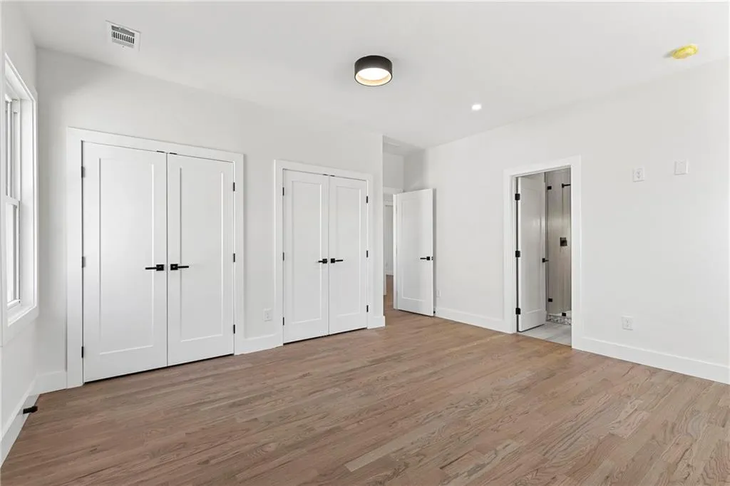 Unfurnished bedroom featuring two closets and wood finished floors