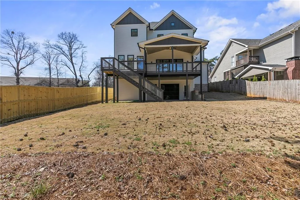 Rear view of house with a fenced backyard, a wooden deck, board and batten siding, stairway, and a patio area