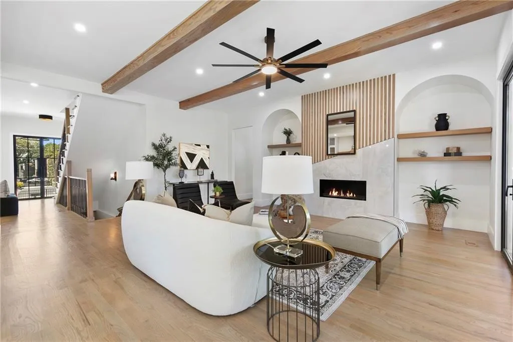 Living room featuring recessed lighting, beam ceiling, light wood-style flooring, built in shelves, and a lit fireplace