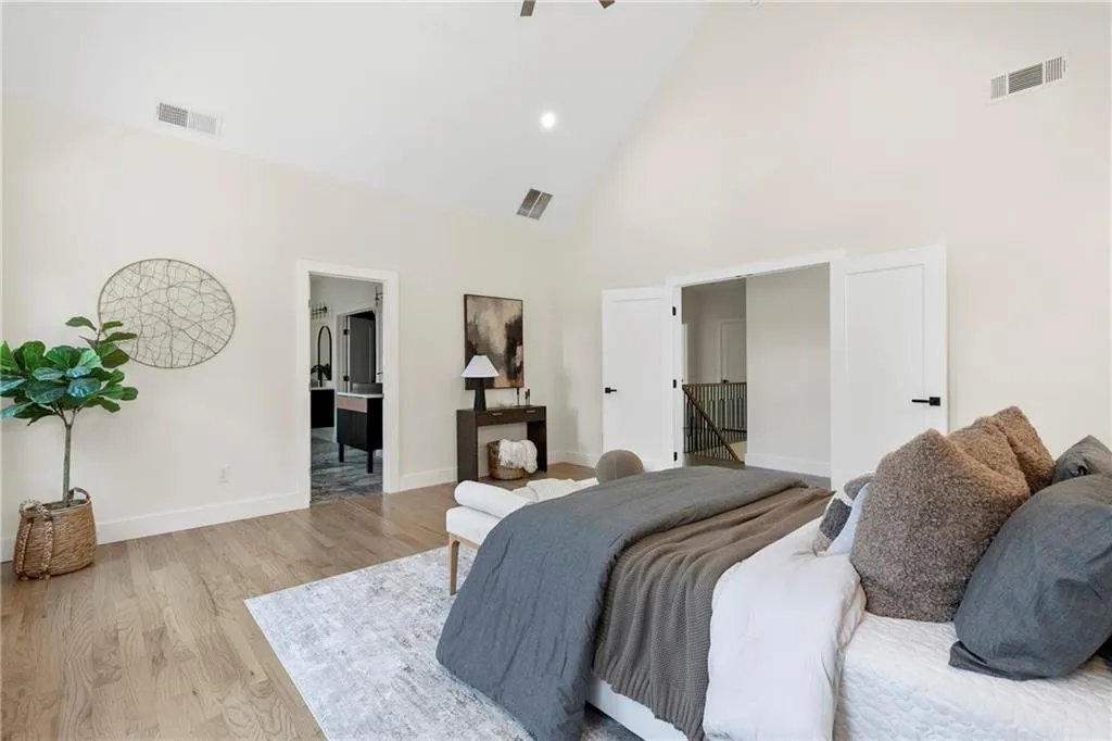Bedroom with high vaulted ceiling, wood finished floors, ceiling fan, ensuite bathroom, and recessed lighting