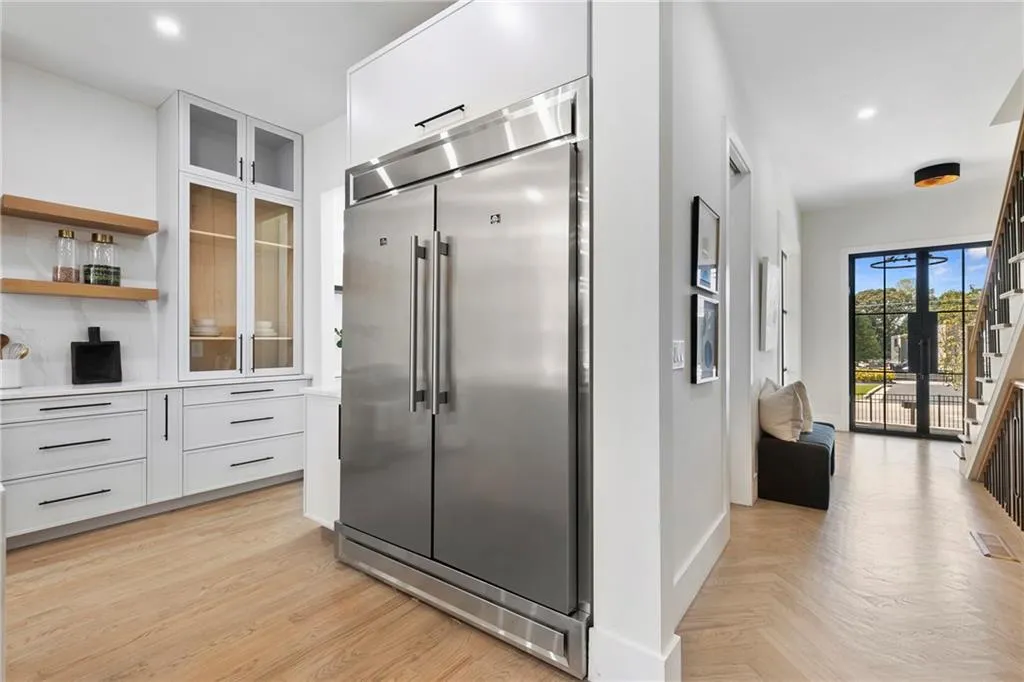 Kitchen with open shelves, glass insert cabinets, white cabinets, built in refrigerator, and recessed lighting