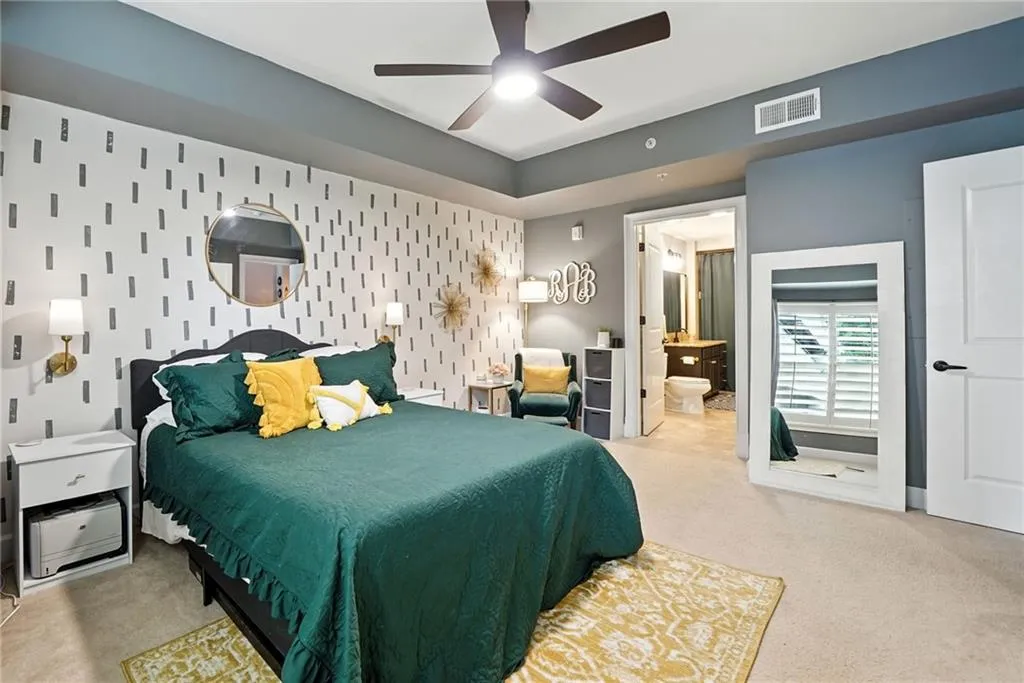 Bedroom with carpet, an accent wall, ceiling fan, and connected bathroom