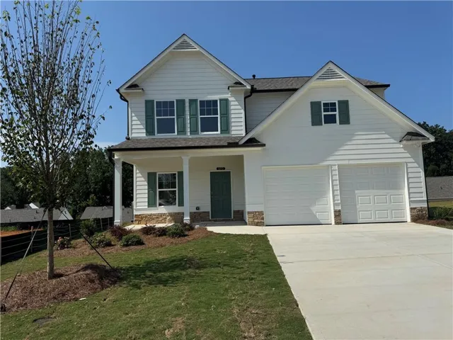 White siding exterior with green shutters, stone accents, two-car garage, and a covered porch entry