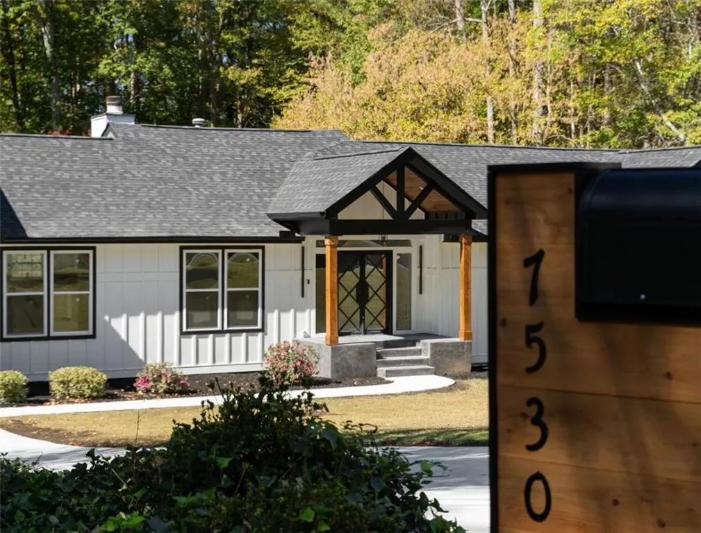 View of front facade featuring roof with shingles, a chimney, and board and batten siding