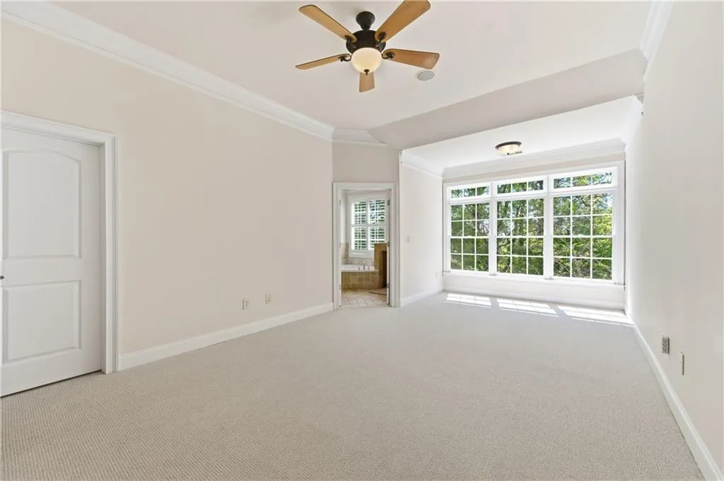 Empty room featuring light carpet, crown molding, and a ceiling fan