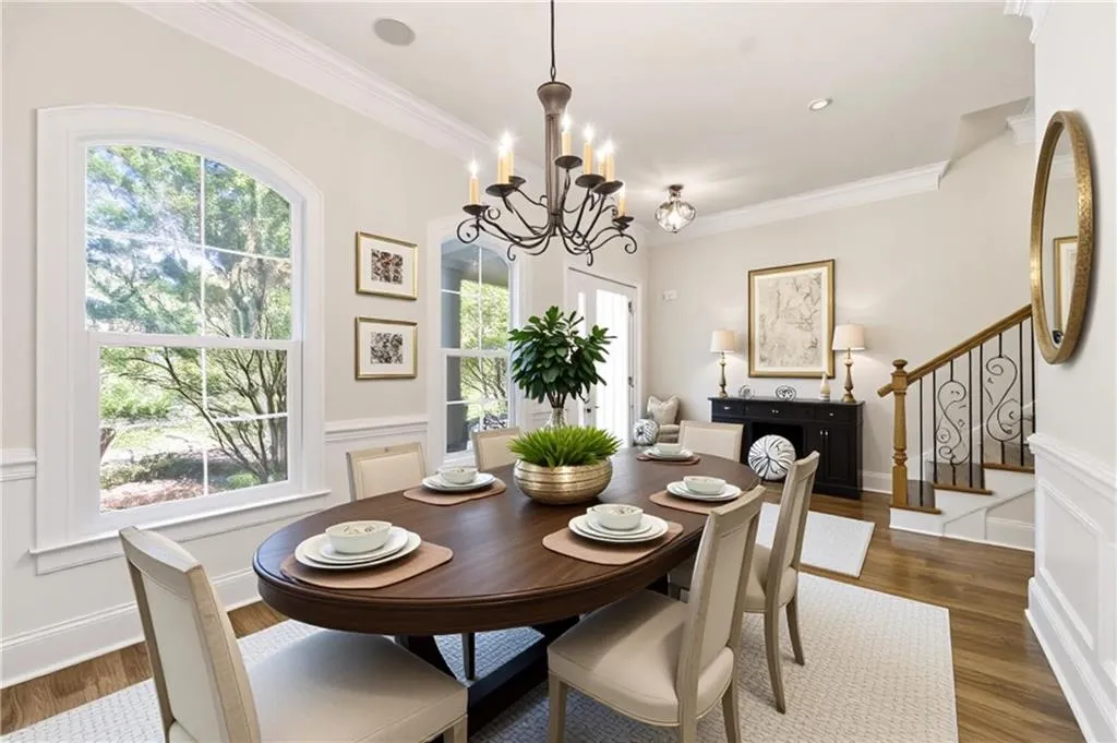 Dining room with wainscoting, a decorative wall, ornamental molding, a chandelier, and dark wood-style flooring