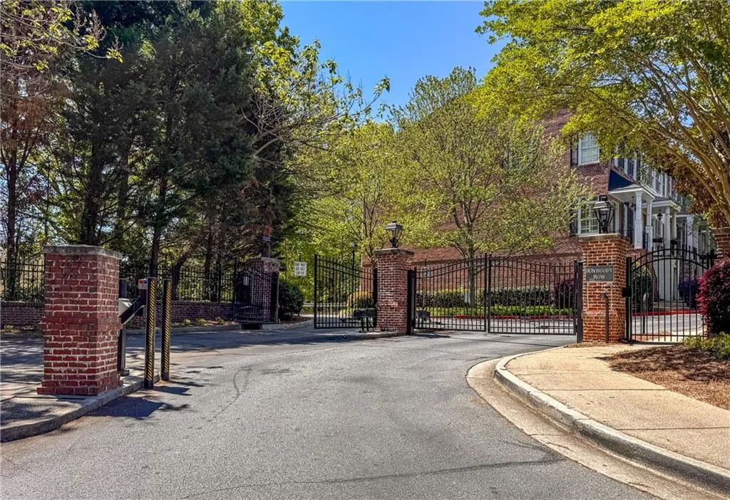 View of asphalt street featuring curbs, a gated entry, street lights, and a gate