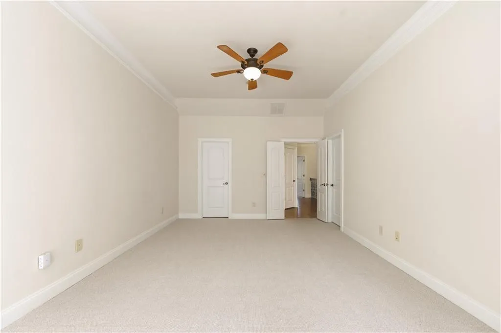 Unfurnished bedroom featuring carpet flooring, crown molding, and ceiling fan