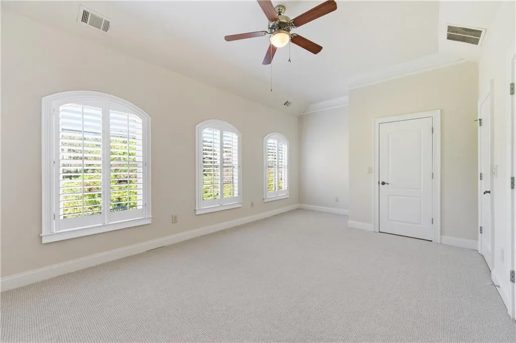 Spare room featuring light colored carpet, lofted ceiling, ceiling fan, and ornamental molding