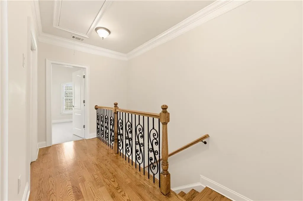 Staircase with wood finished floors and crown molding